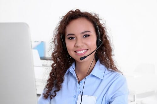 Smiling customer service representative wearing headset at computer